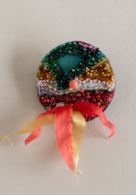Huge wool disk with green red and gold beads with a red and gold tails